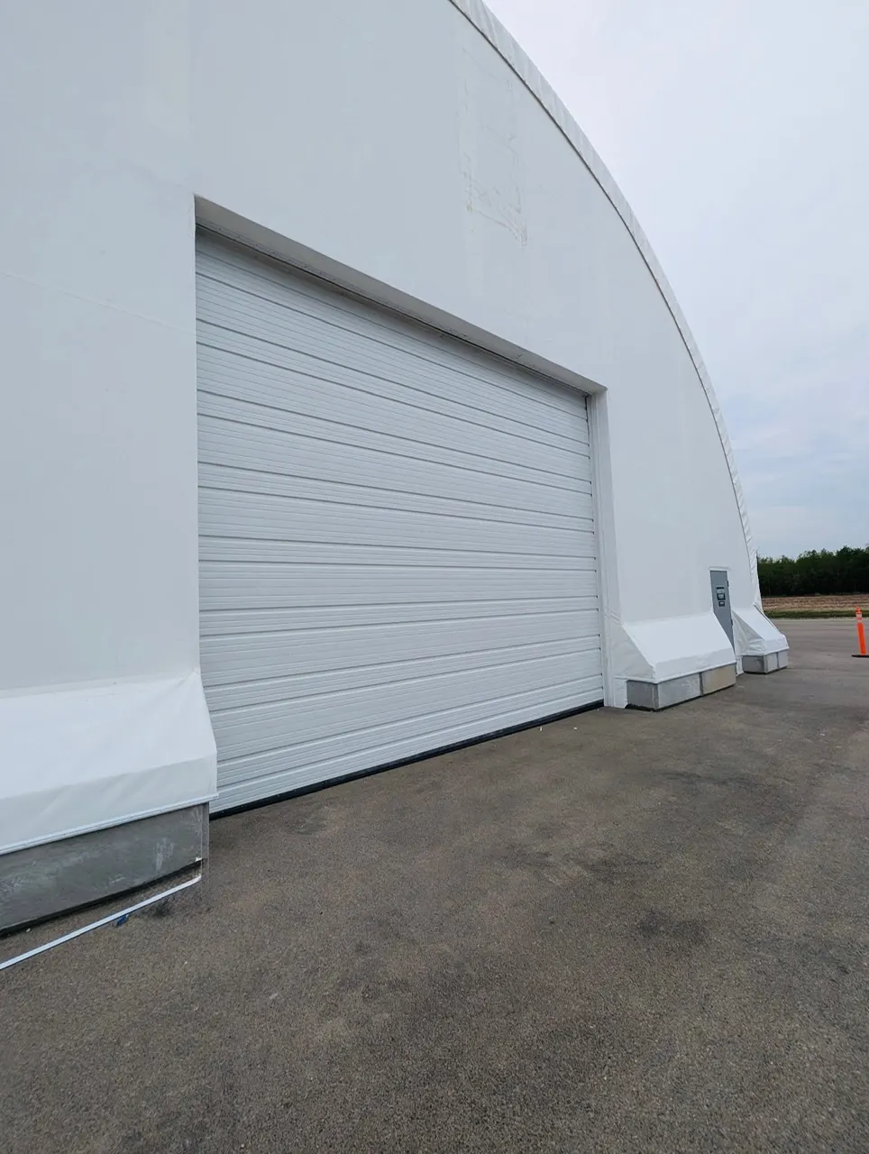 Fabric equipment storage building with large overhead door