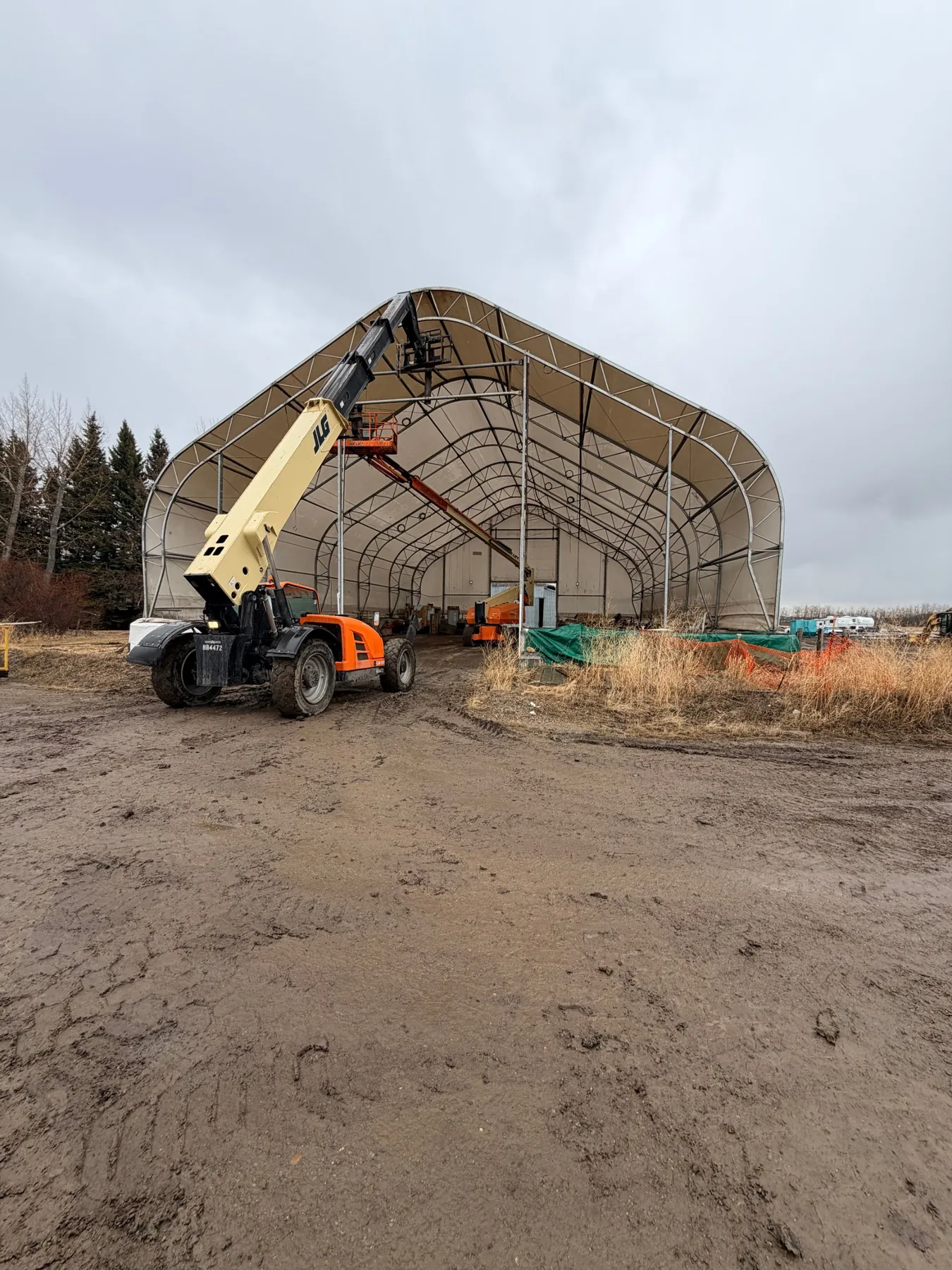 Telehandler and boom lift working on a large gable fabric building during a relocation in Edmonton, Alberta